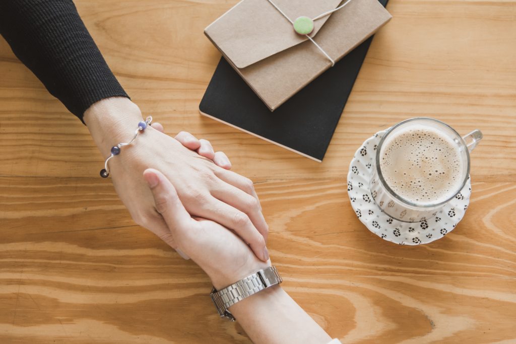 deux femmes qui serrent la main devant un café