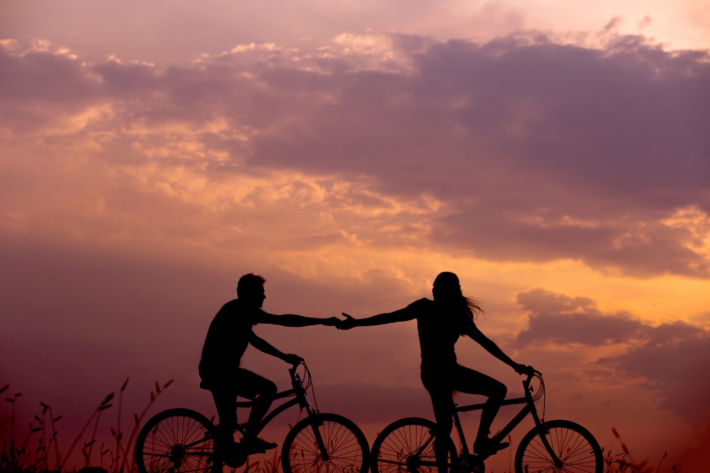 Homme et femme à vélo se tenant la main 