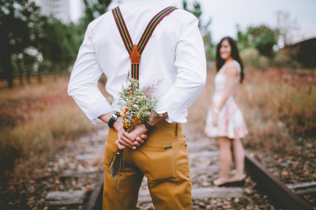 homme qui tient un bouquet de fleur caché